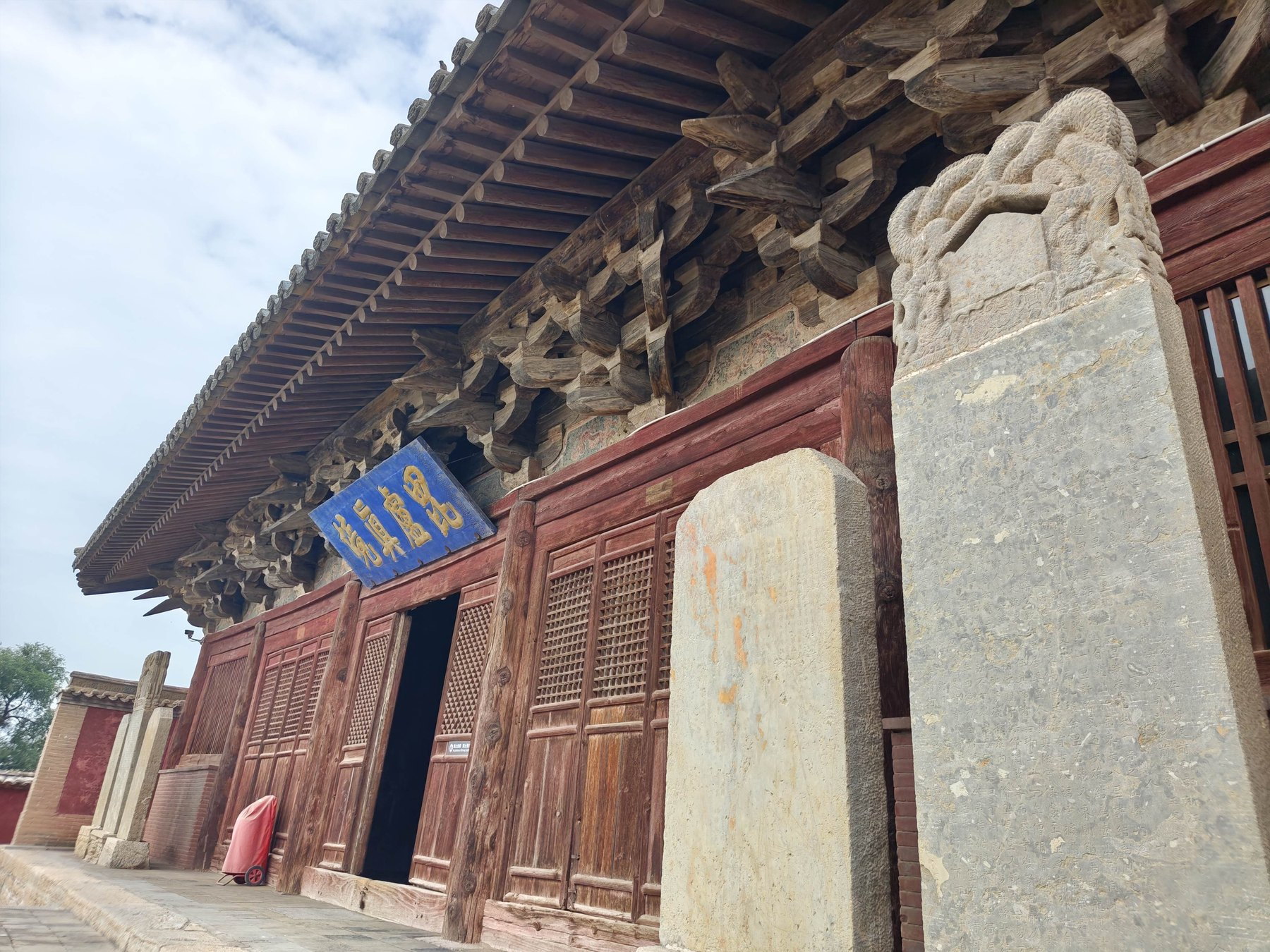 定襄洪福寺大雄宝殿前檐木构、层叠斗拱、蓝底匾额与殿前石碑